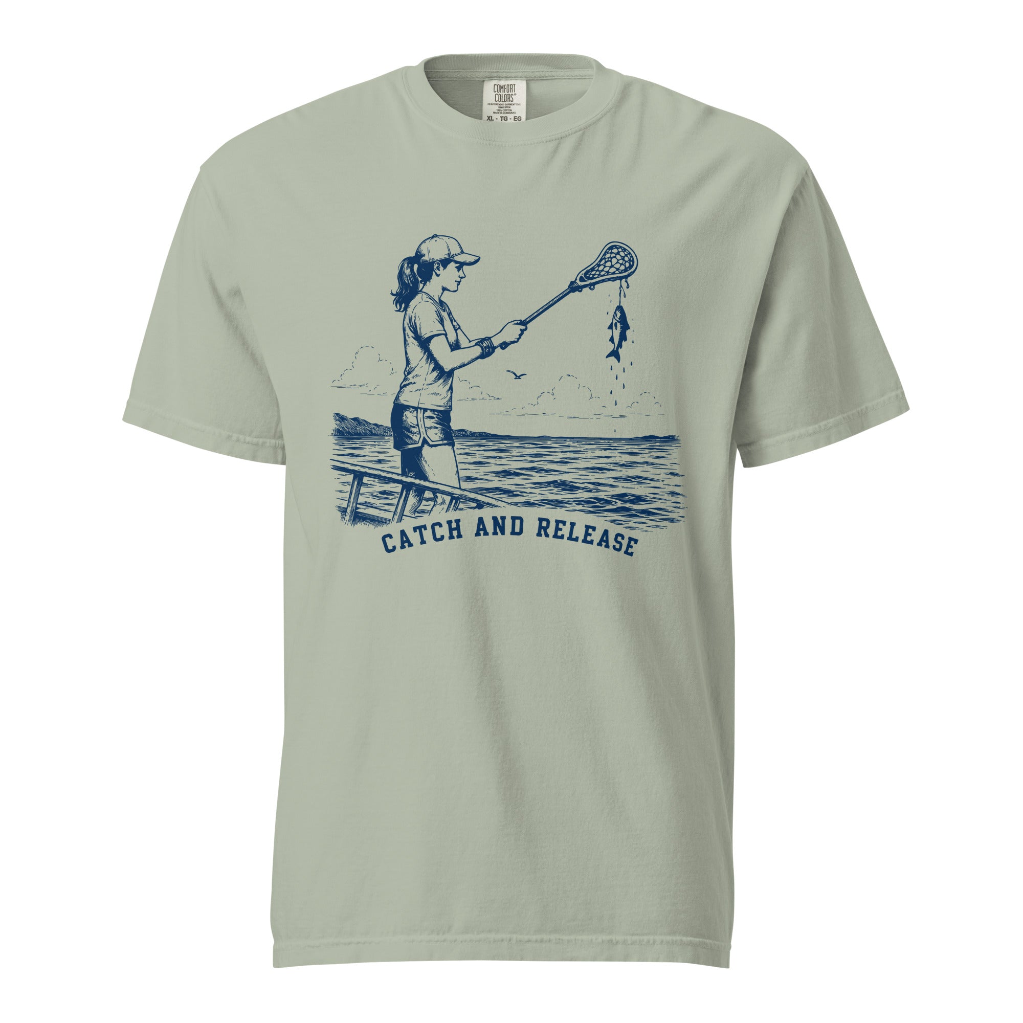 Lacrosse shirt with the GO2X Catch and Release design, a woman on a dock holding a lacrosse stick with a fish hanging from the head