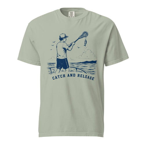 Lacrosse shirt with the GO2X Catch and Release design, a man on a dock holding a lacrosse stick with a fish hanging from the head