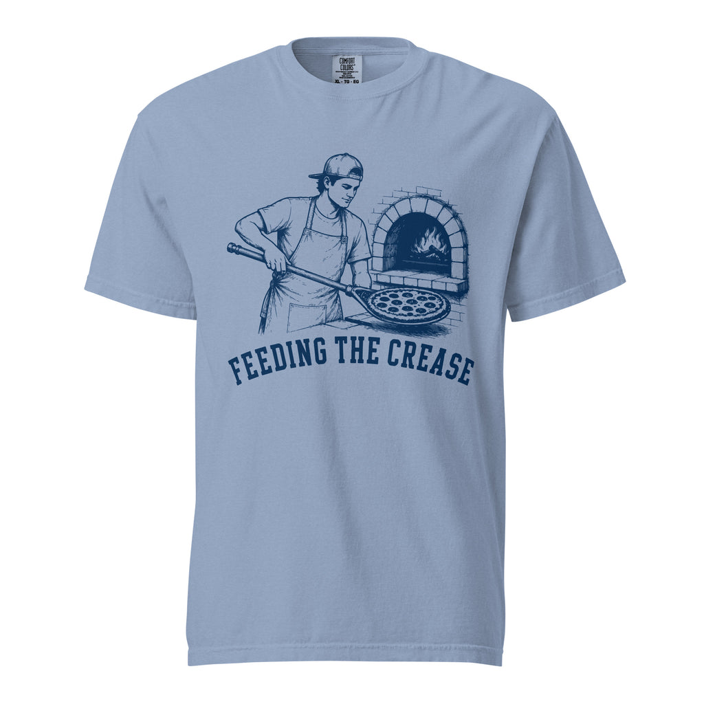 Lacrosse shirt with the GO2X Feeding the Crease design, a man sliding a pizza into a wood-fired oven with a lacrosse stick