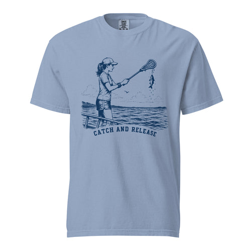 Lacrosse shirt with the GO2X Catch and Release design, a girl on a dock holding a lacrosse stick with a fish hanging from the head